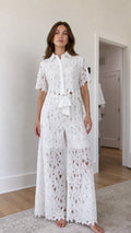 Front view of woman wearing white floral lace shirt and wide-leg pants set