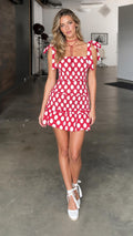 Model wearing red polka dot smocked mini dress, front view