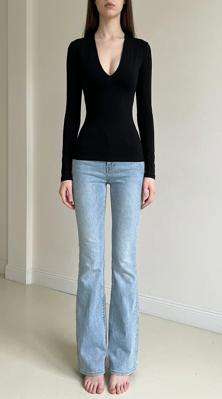 Front view of woman wearing black deep v-neck long sleeve top with light wash jeans