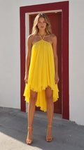 Front view of woman wearing yellow halter neck high-low dress