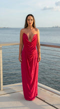 Front view of woman wearing fuchsia strapless cowl neck maxi dress by the water