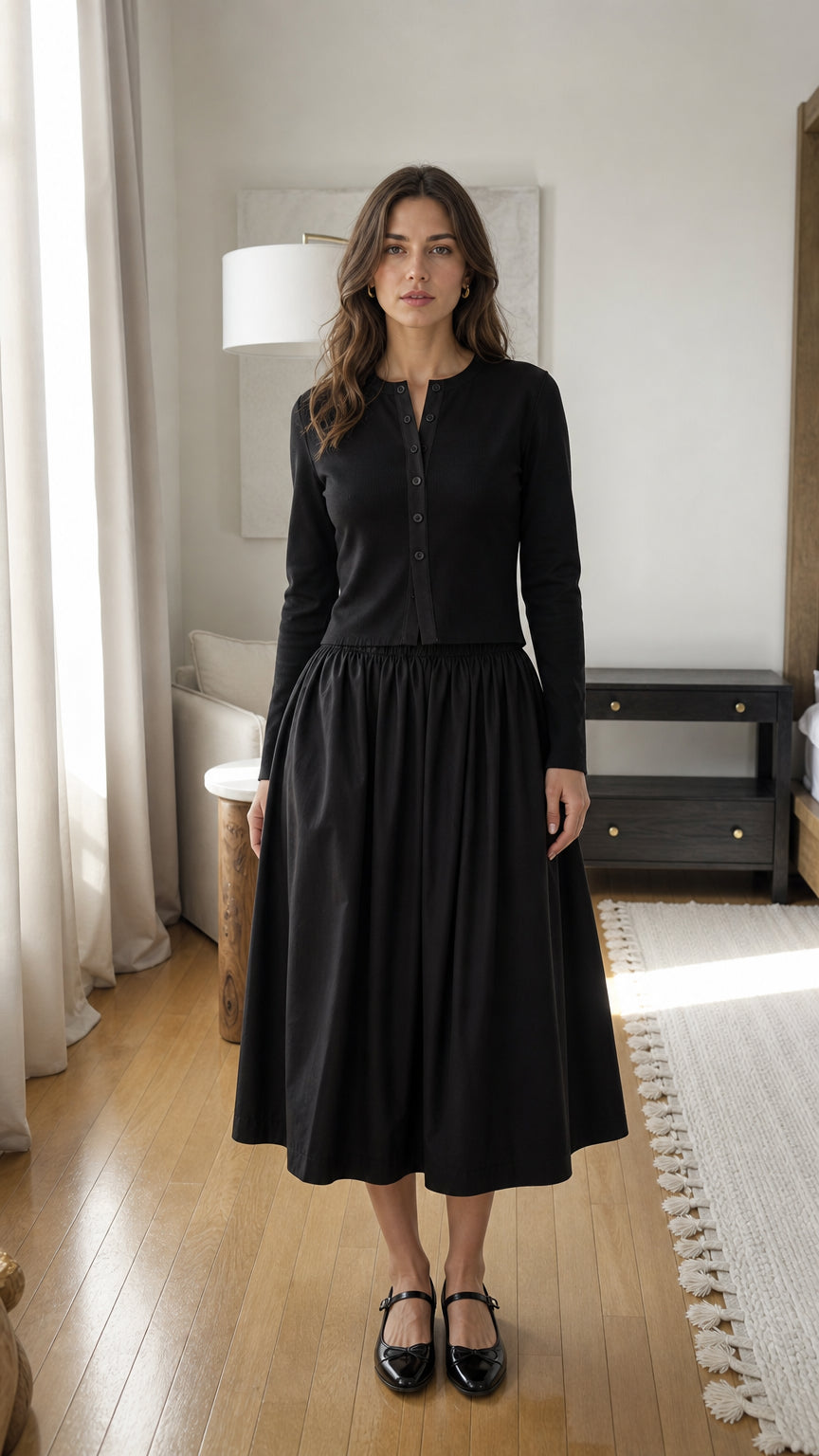Woman wearing black long-sleeve ribbed button-down top and midi skirt set, front view