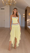 Front view of model wearing yellow embellished corset and asymmetric skirt set