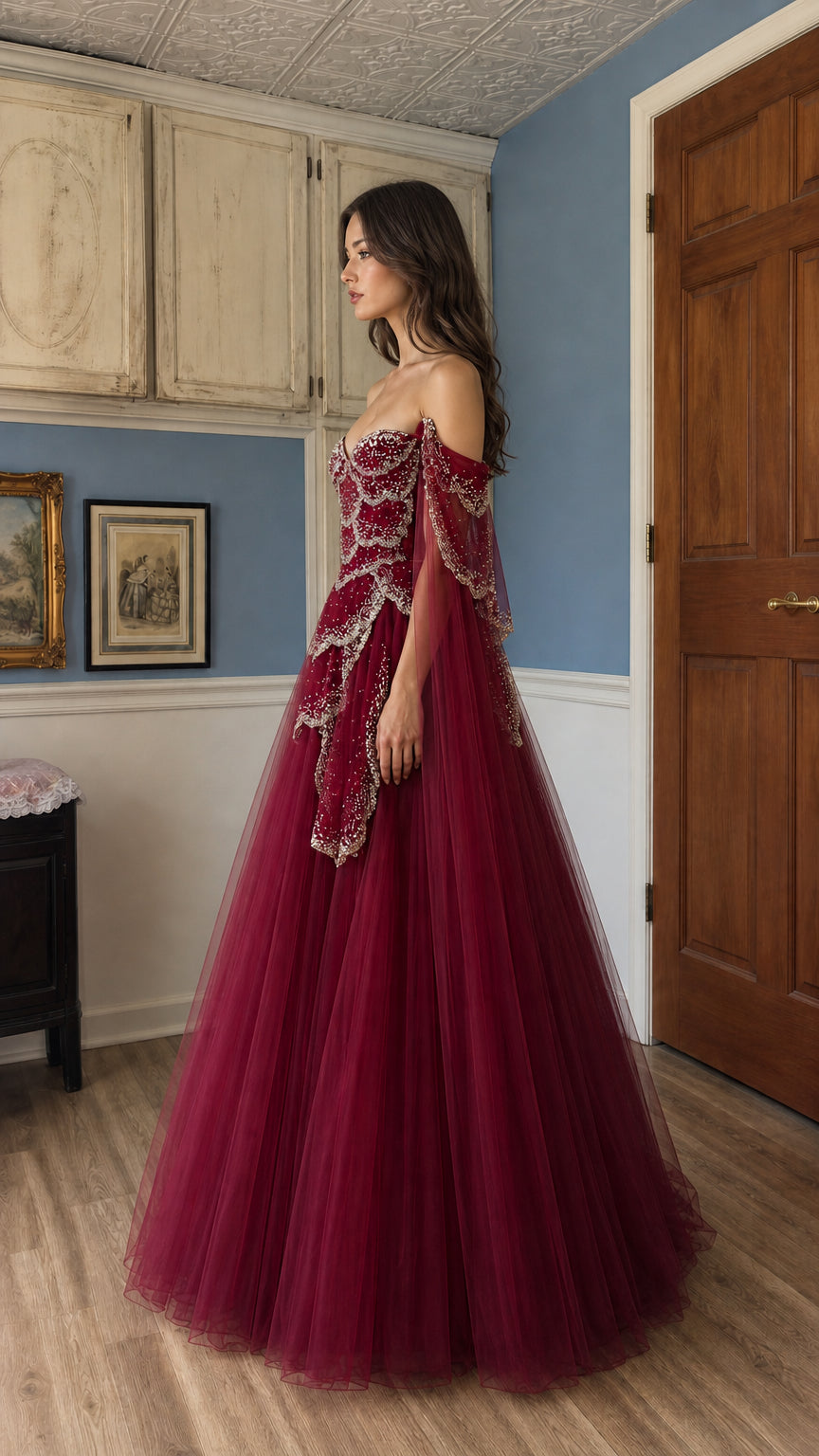 Side profile view of burgundy evening gown with dramatic cape sleeves