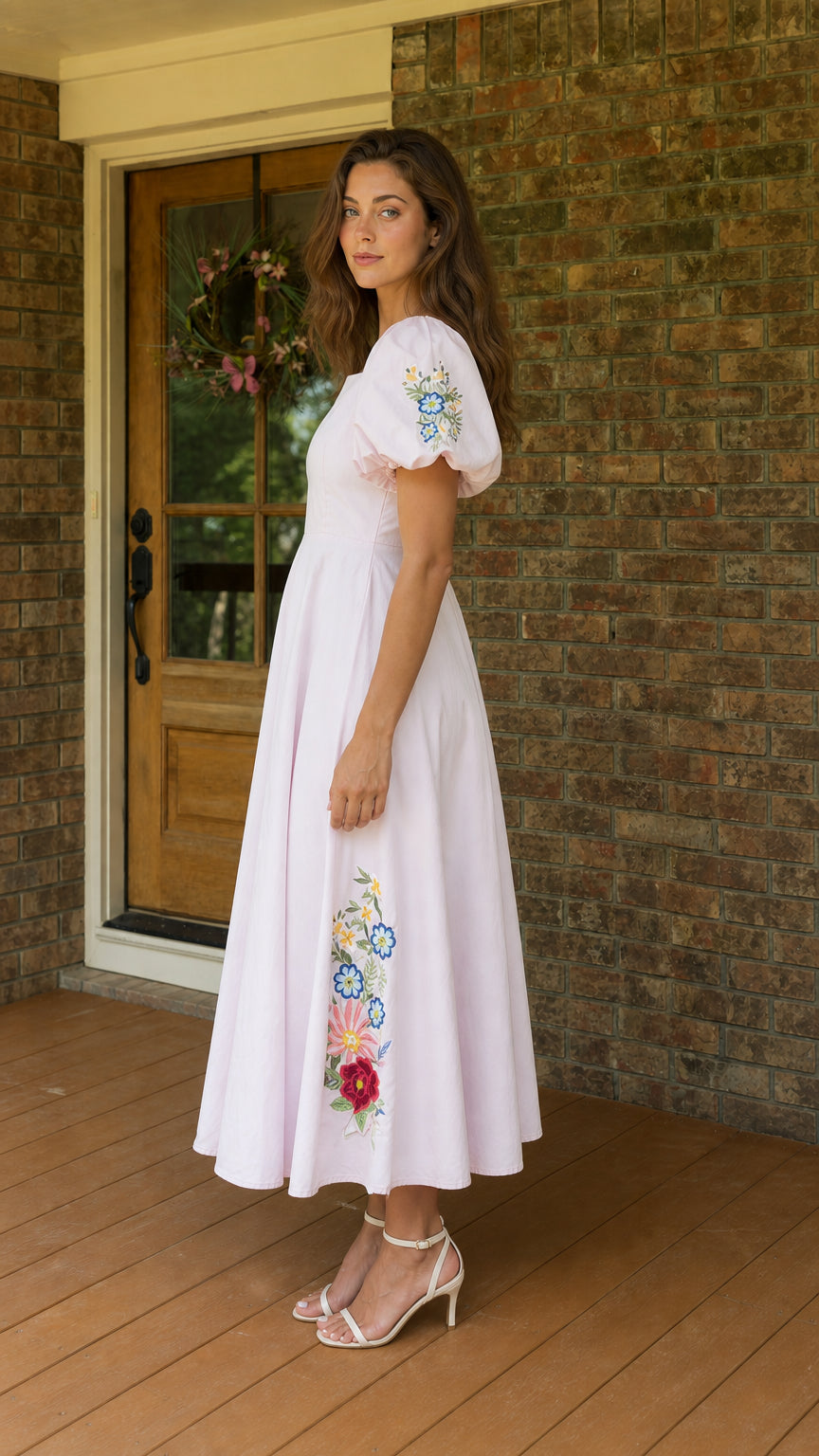 Side profile of woman in pink embroidered midi dress showing side hem detail