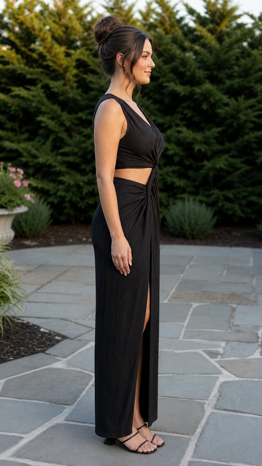 Side profile view of woman wearing black maxi dress with side cutout and slit