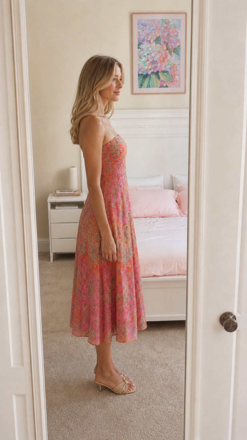Woman wearing pink strapless paisley midi dress side view