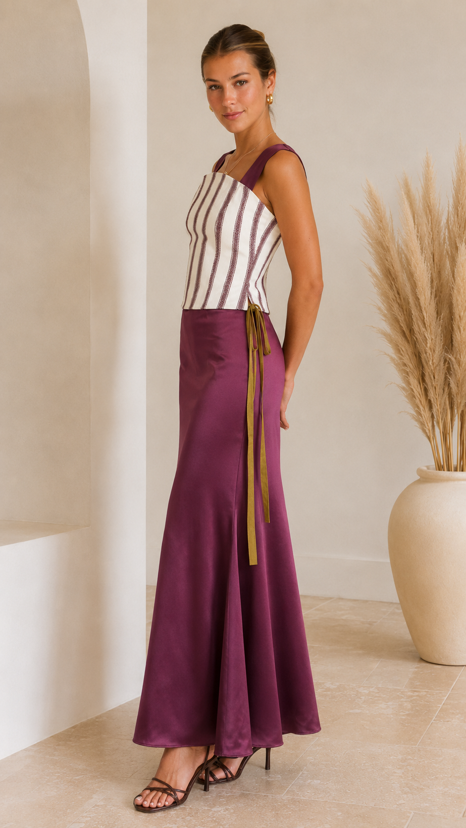 Side view of plum striped corset maxi dress with flared satin-look hem