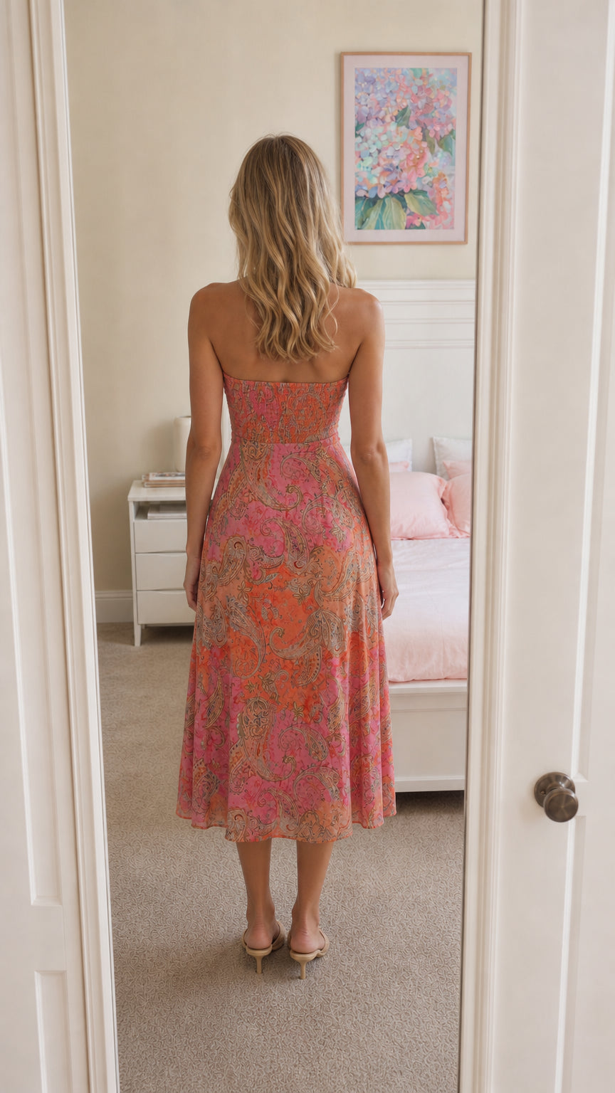 Woman wearing pink strapless paisley midi dress back view