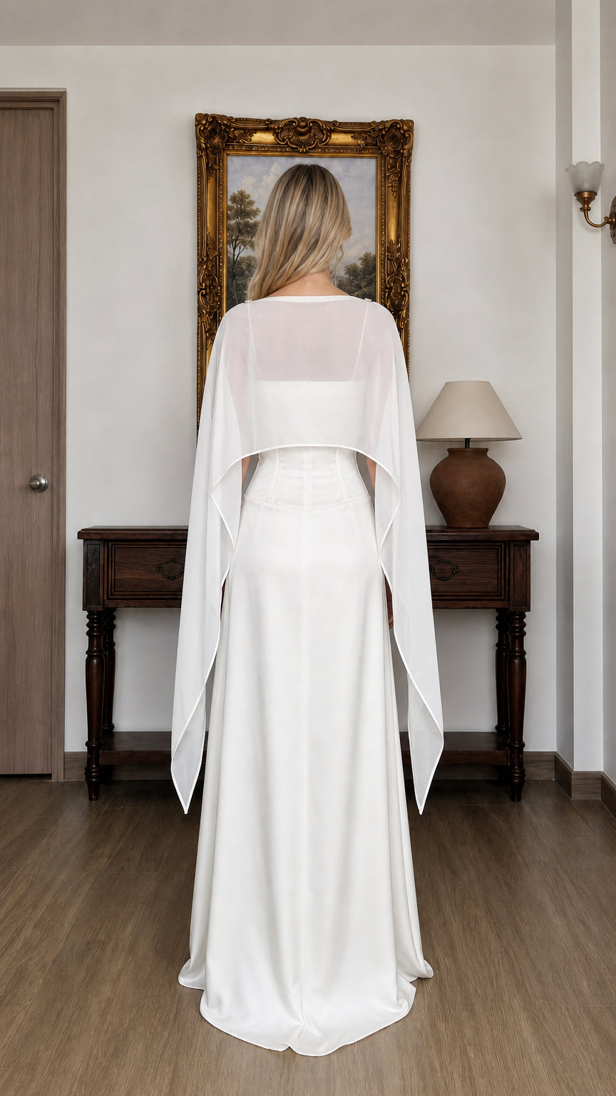 Back view of woman wearing white evening dress with flowing cape