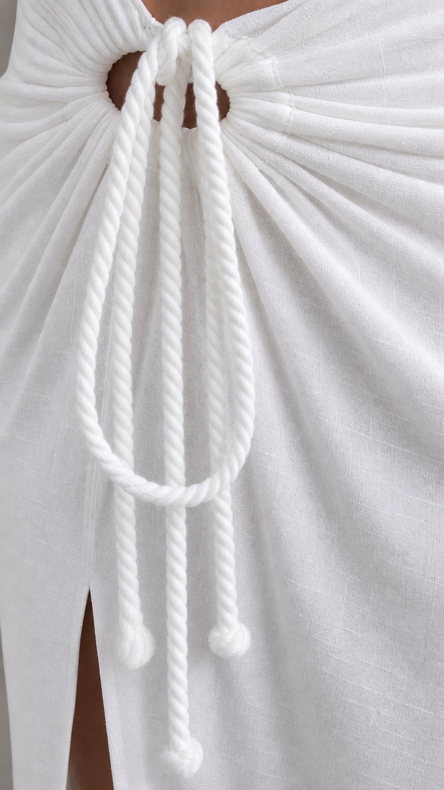 Close-up of decorative rope tie detail on white skirt