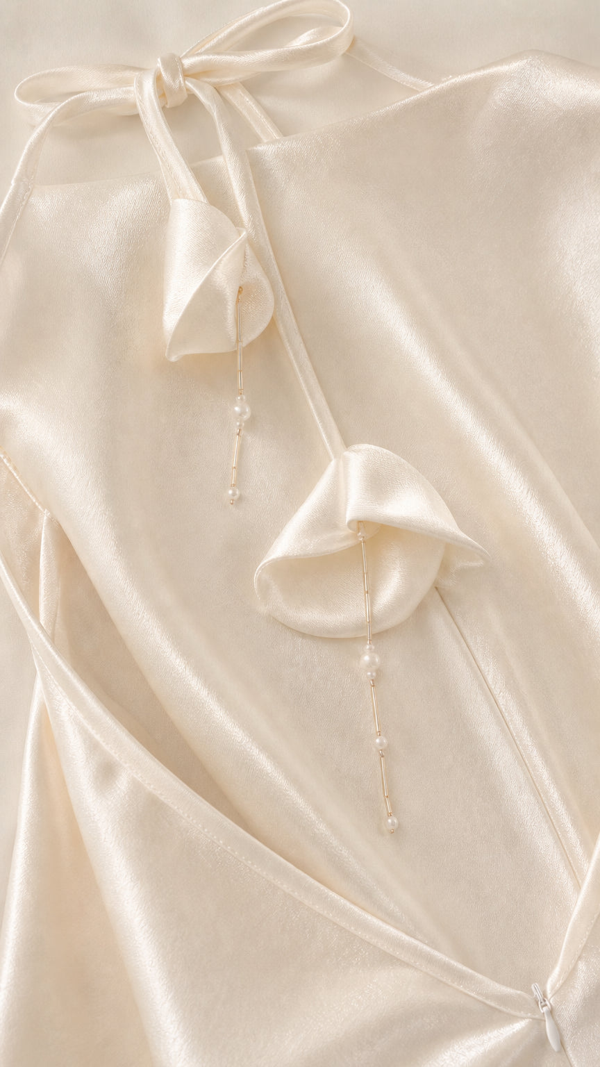 Close-up detail of back tie straps with floral and bead drops on white satin