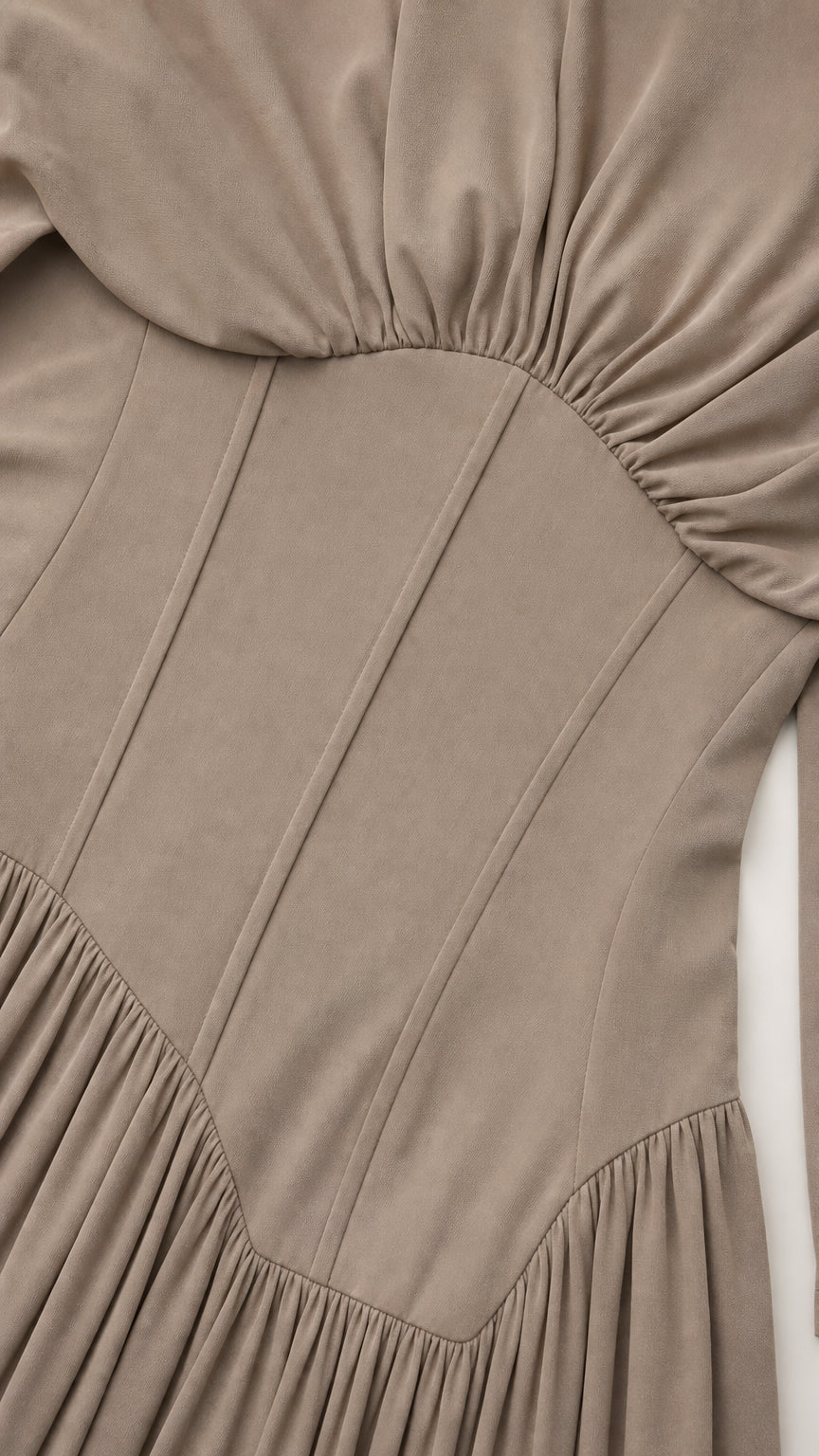 Close-up detail of structured corset waist and pleated fabric on taupe dress