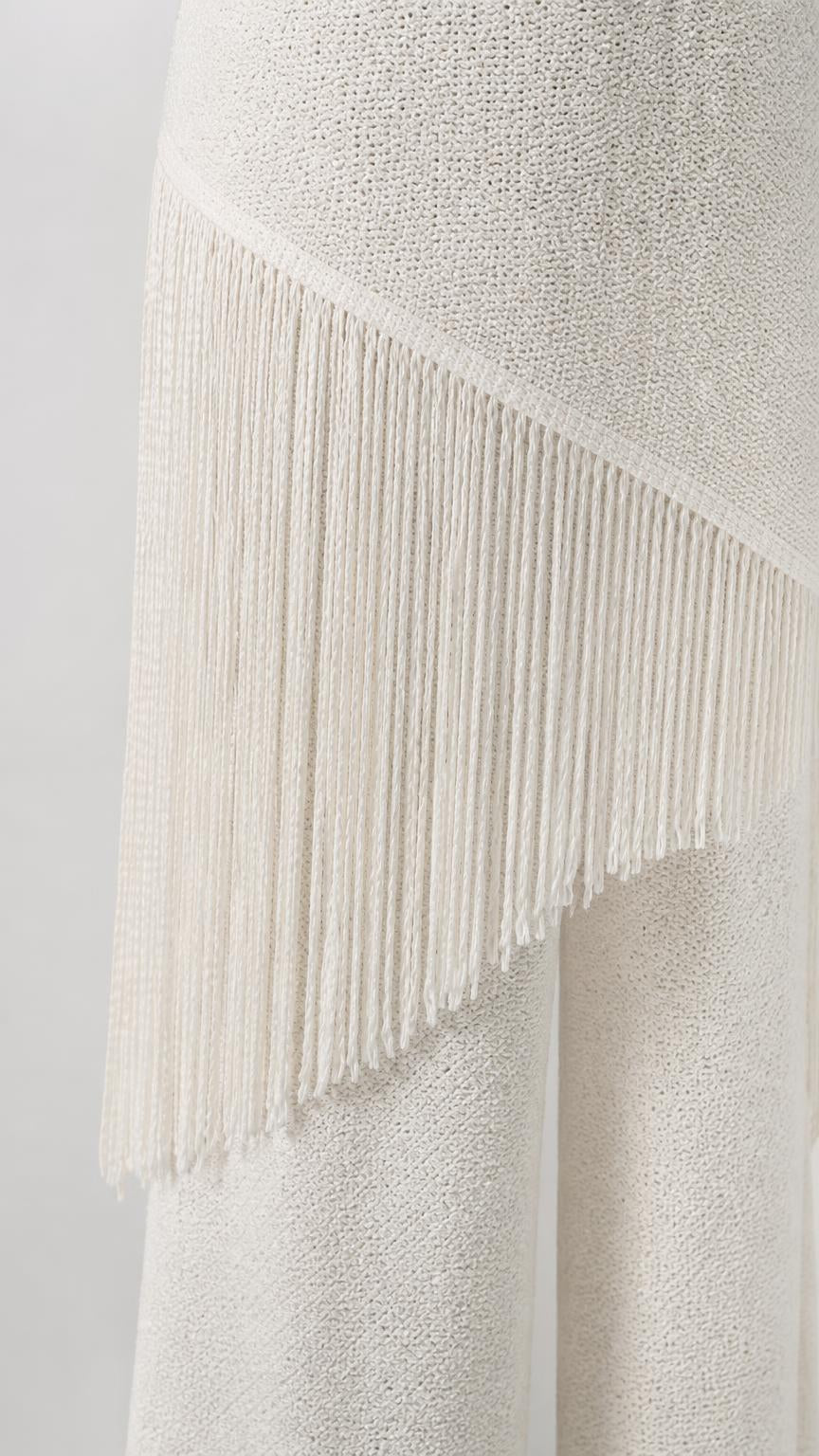 Close-up detail of white fringe overlay on knit jumpsuit