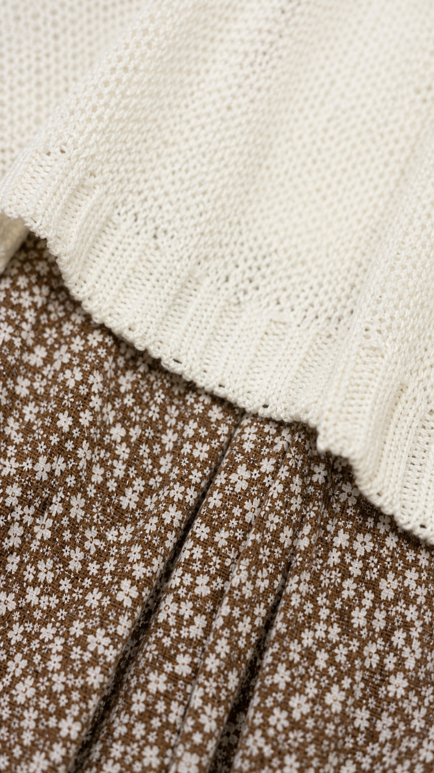 Close-up detail of white knit texture and brown floral skirt fabric
