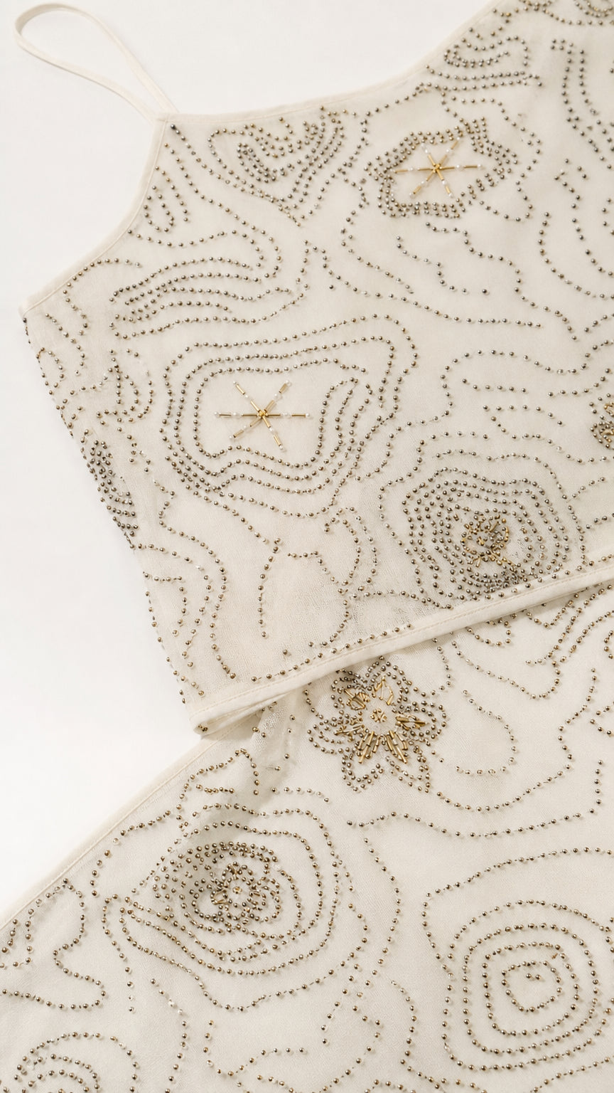 Close-up detail of intricate beadwork on cream dress