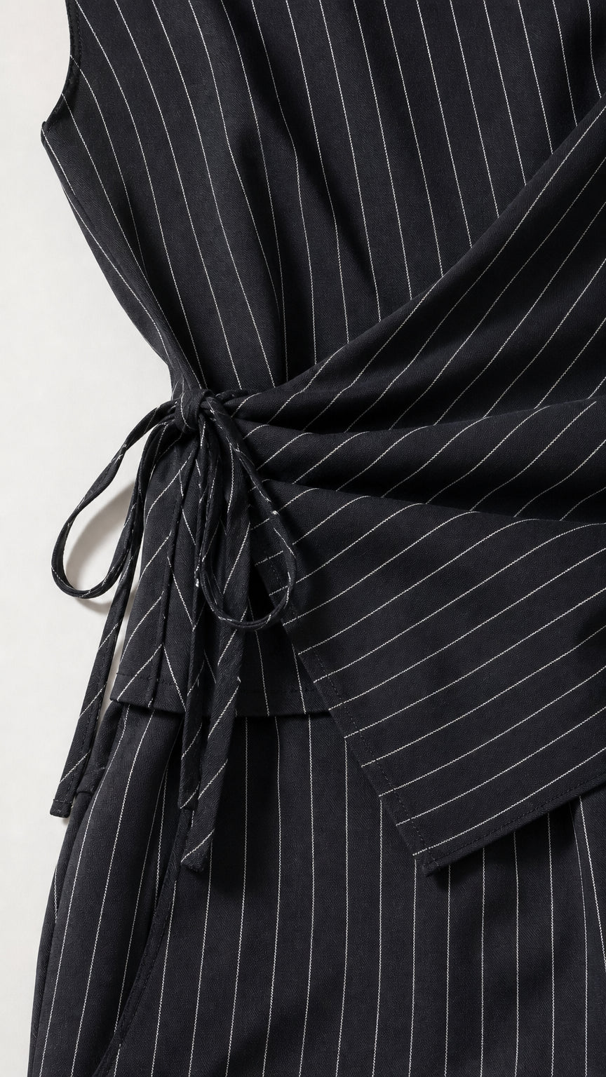 Close-up detail of the side tie wrap waist on the pinstripe jumpsuit