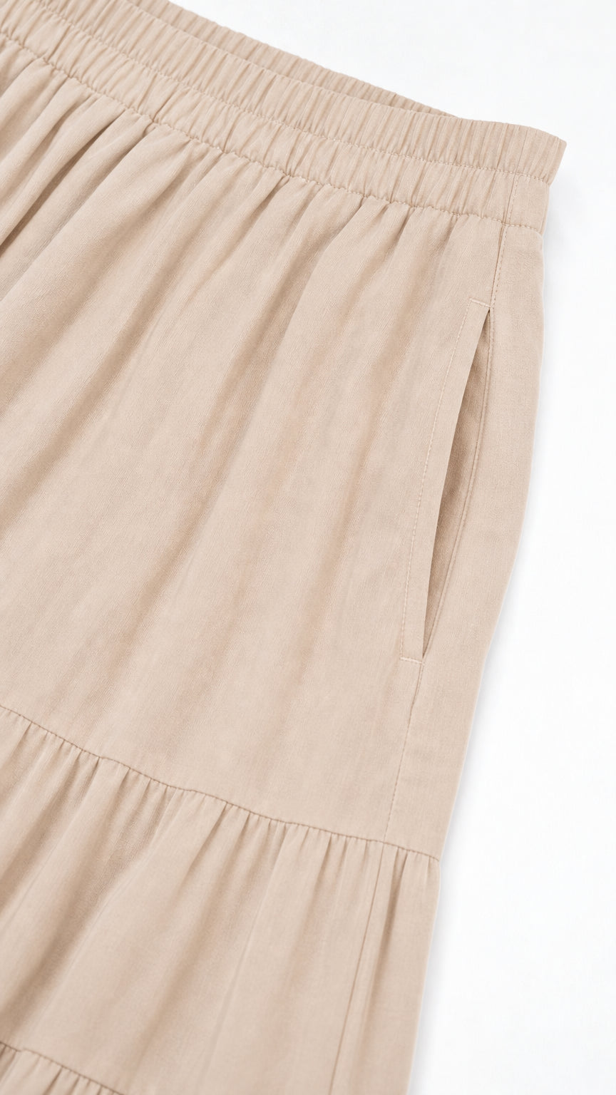 Close-up detail of side pocket and elastic waistband on beige skirt