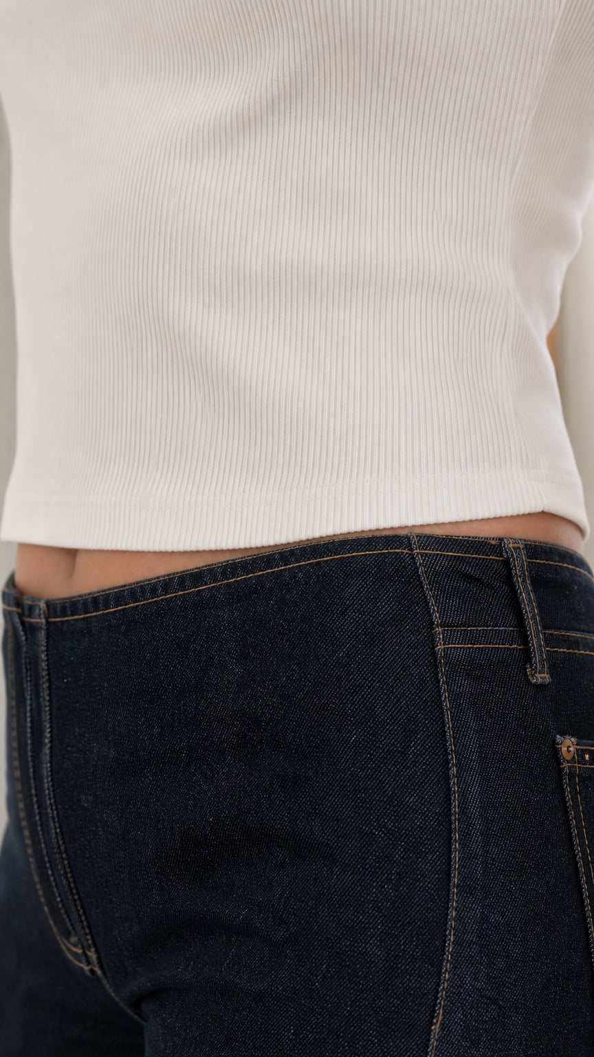 Close-up detail of white ribbed knit texture and denim waistband
