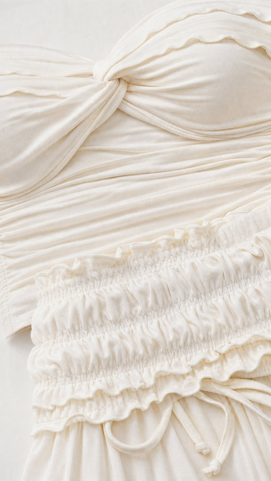 Close-up detail of textured ruching and fabric on the ivory top and skirt