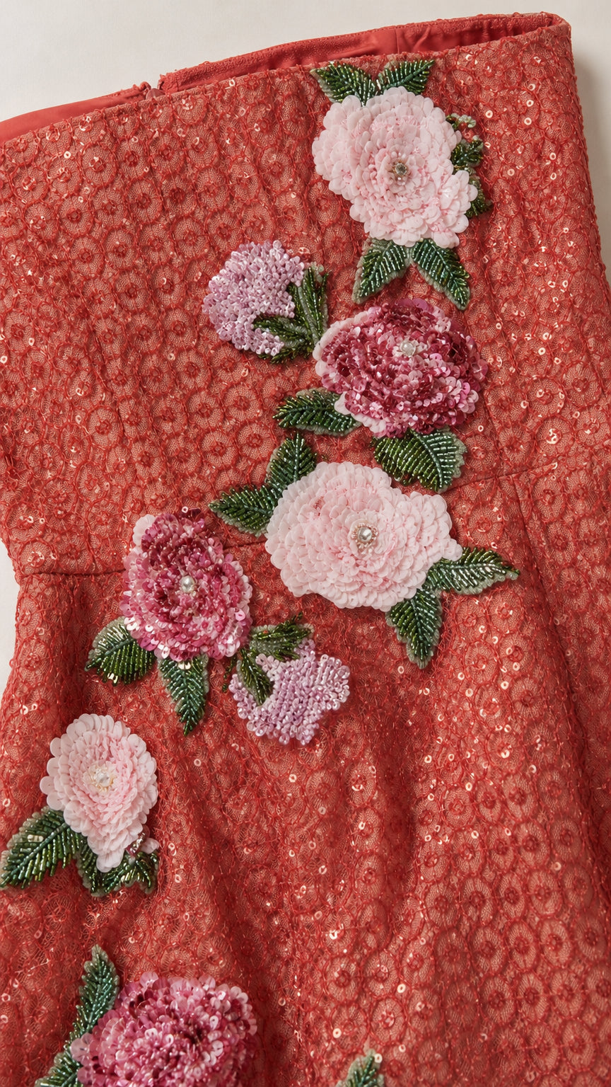 Close-up of red sequin fabric and pink floral appliques