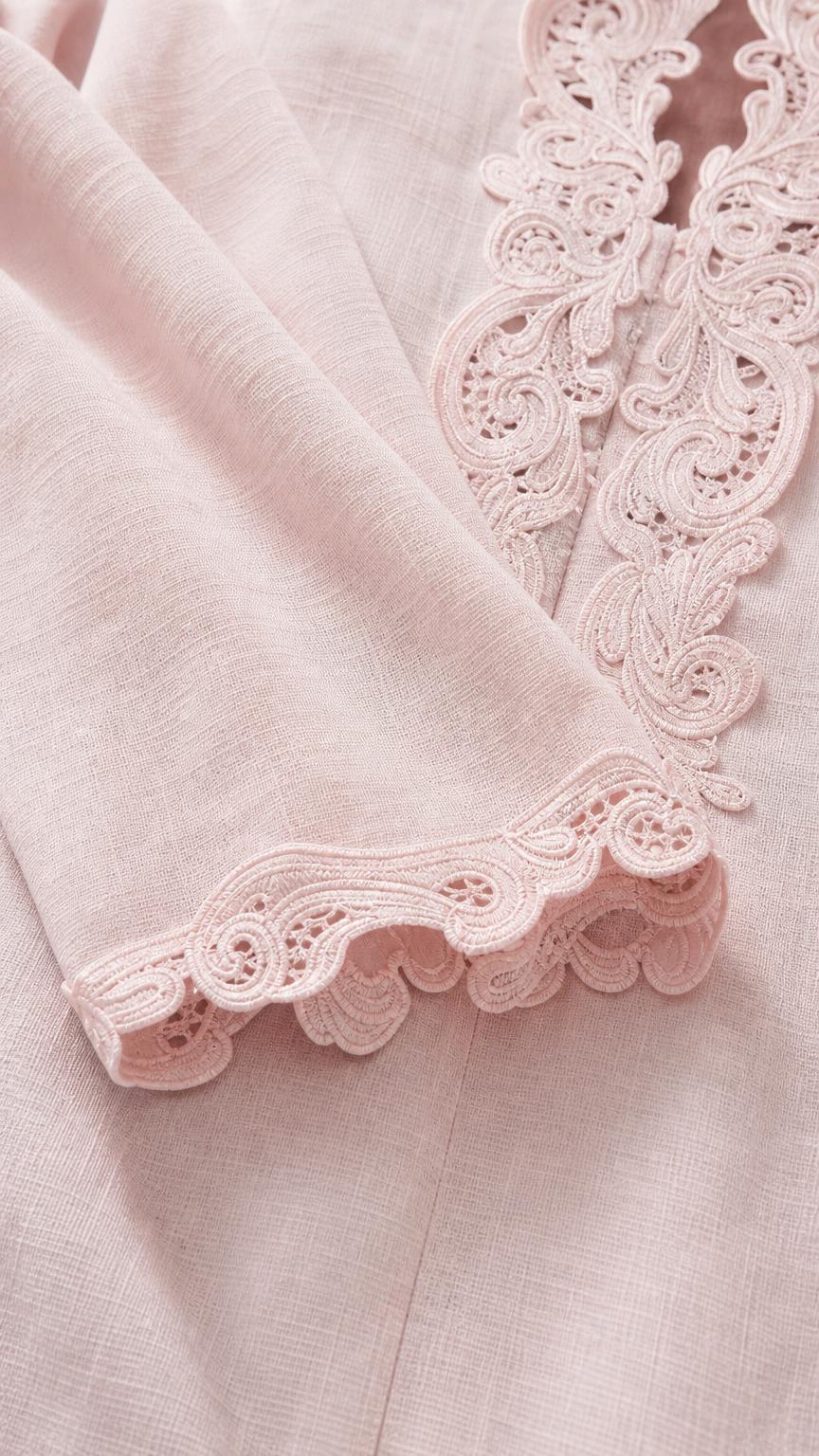 Close-up detail of delicate crocheted lace trim on sleeve and collar