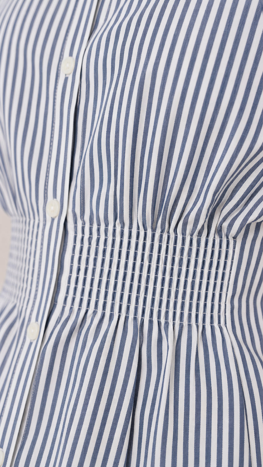 Close-up detail of blue vertical stripes and smocked waist construction