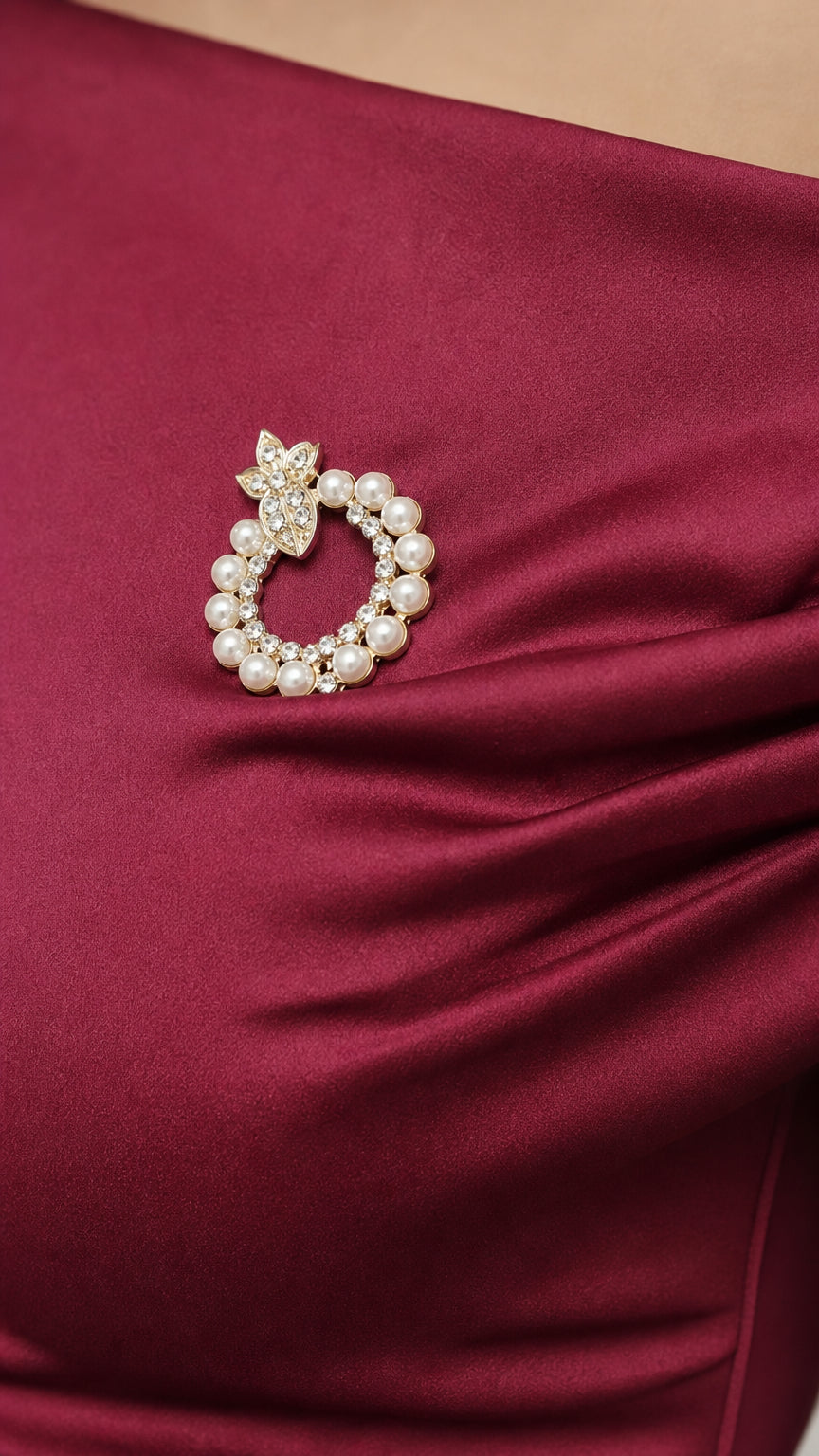 Close-up detail of pearl and crystal brooch on burgundy fabric