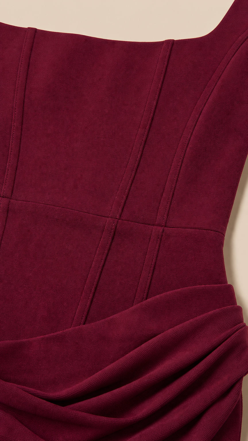 Close-up of bodice seams and draped hip detail on burgundy dress