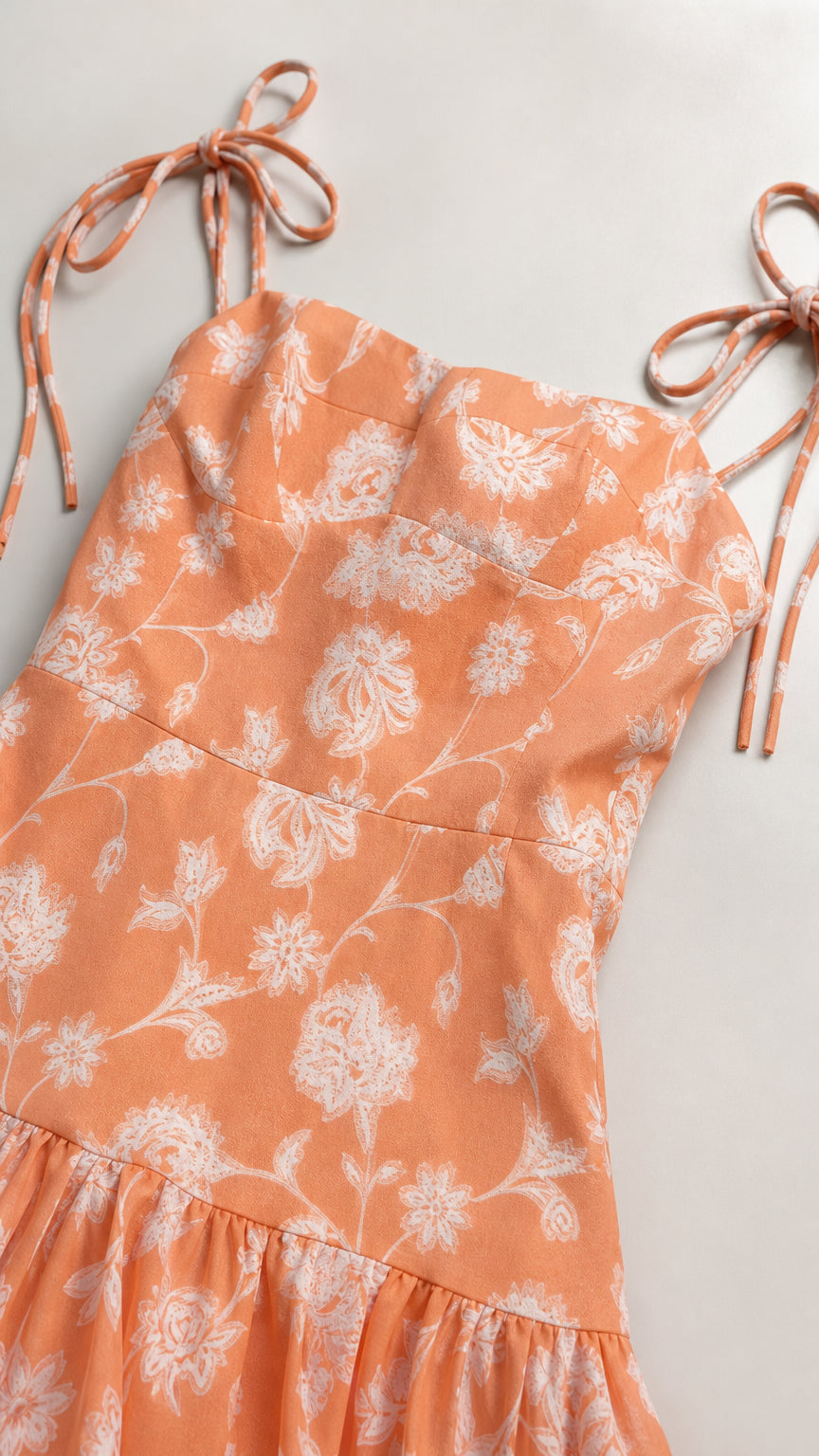 Close-up detail of tie straps and bodice on peach floral dress