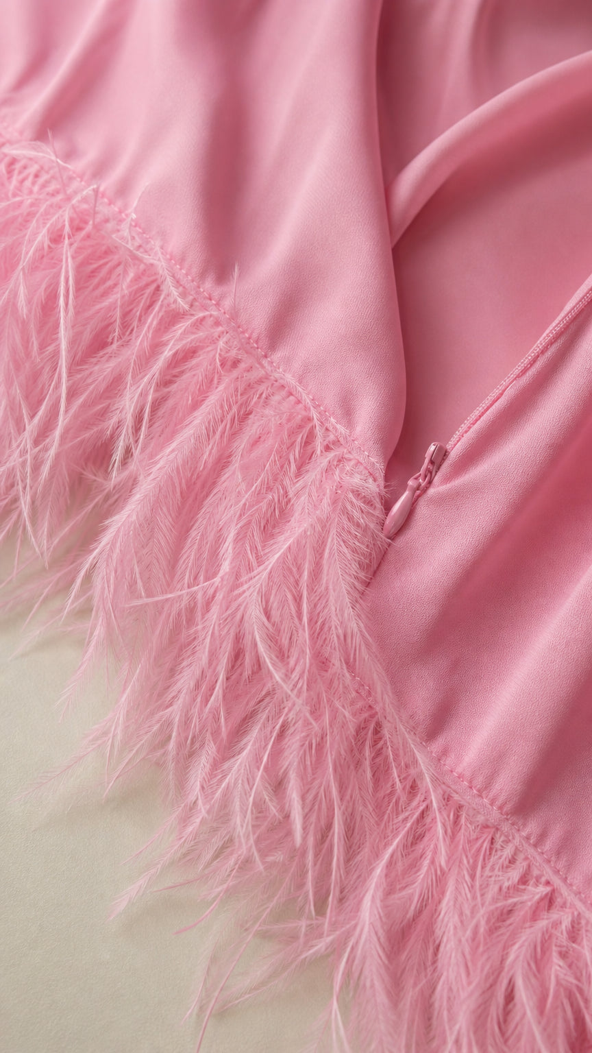 Close up detail of pink dress fabric and feather hem trim with zipper