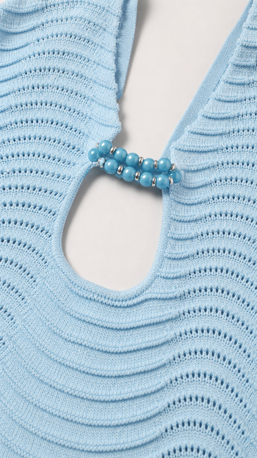 Close-up detail of front cutout and turquoise beaded hardware on light blue knit dress