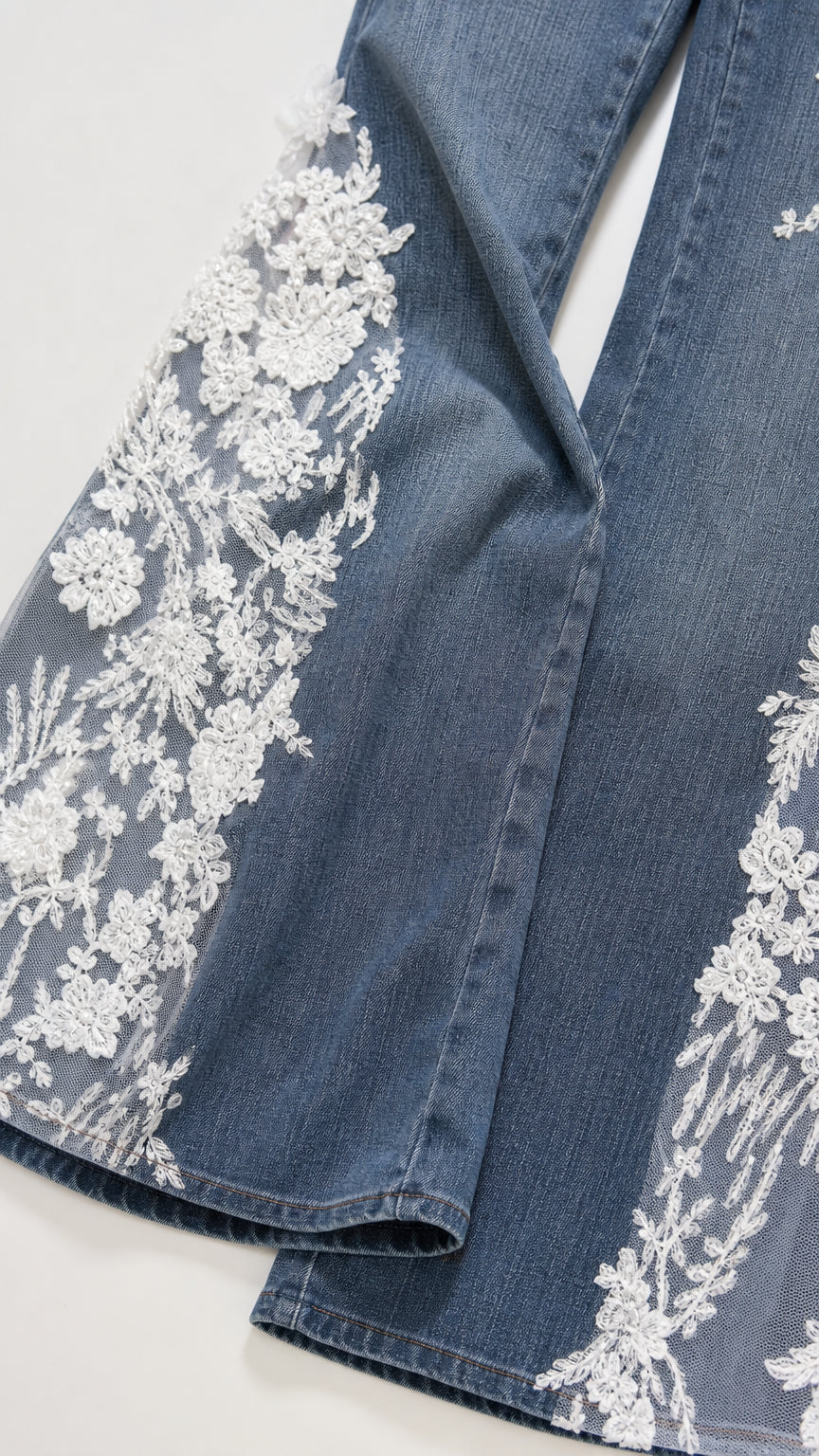 Close-up of intricate white floral lace appliques on denim hem