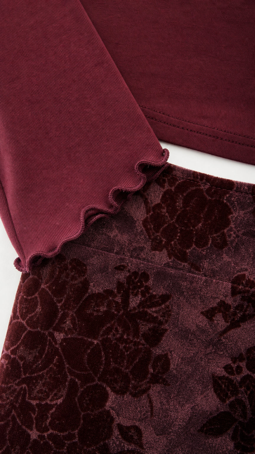 Close-up detail of lettuce-edge cuff and velvet floral skirt texture