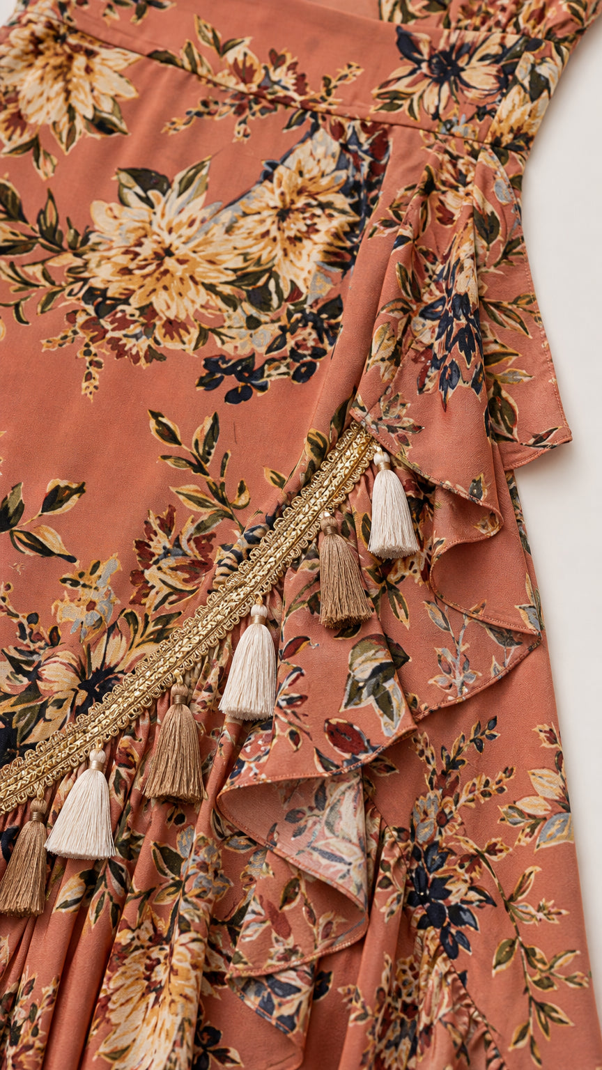 Close-up of tassel trim and ruffles on rust floral wrap dress