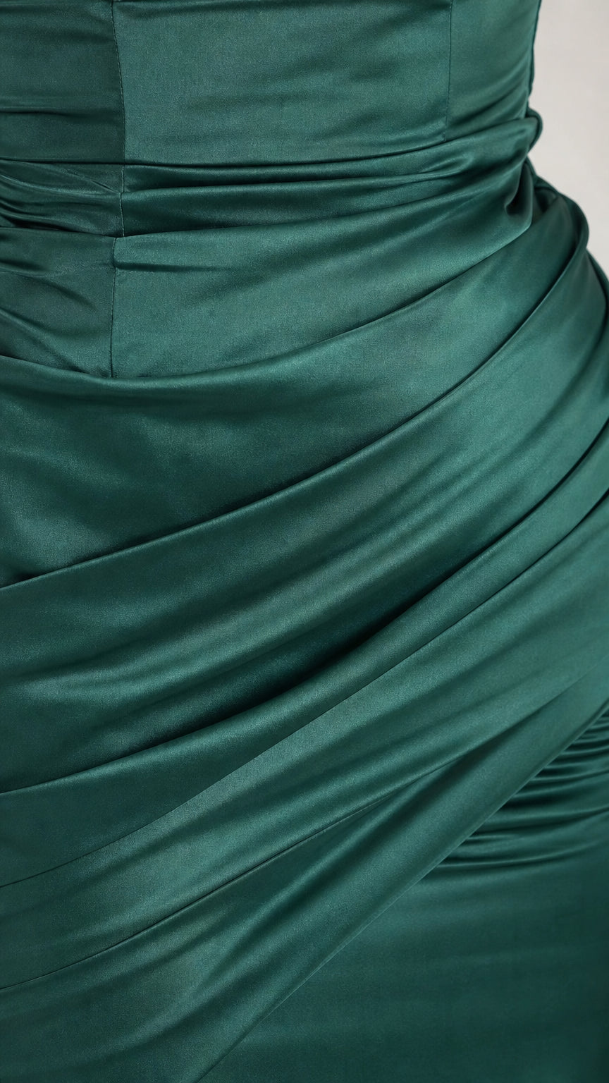 Close-up detail of satin ruching on the emerald green dress