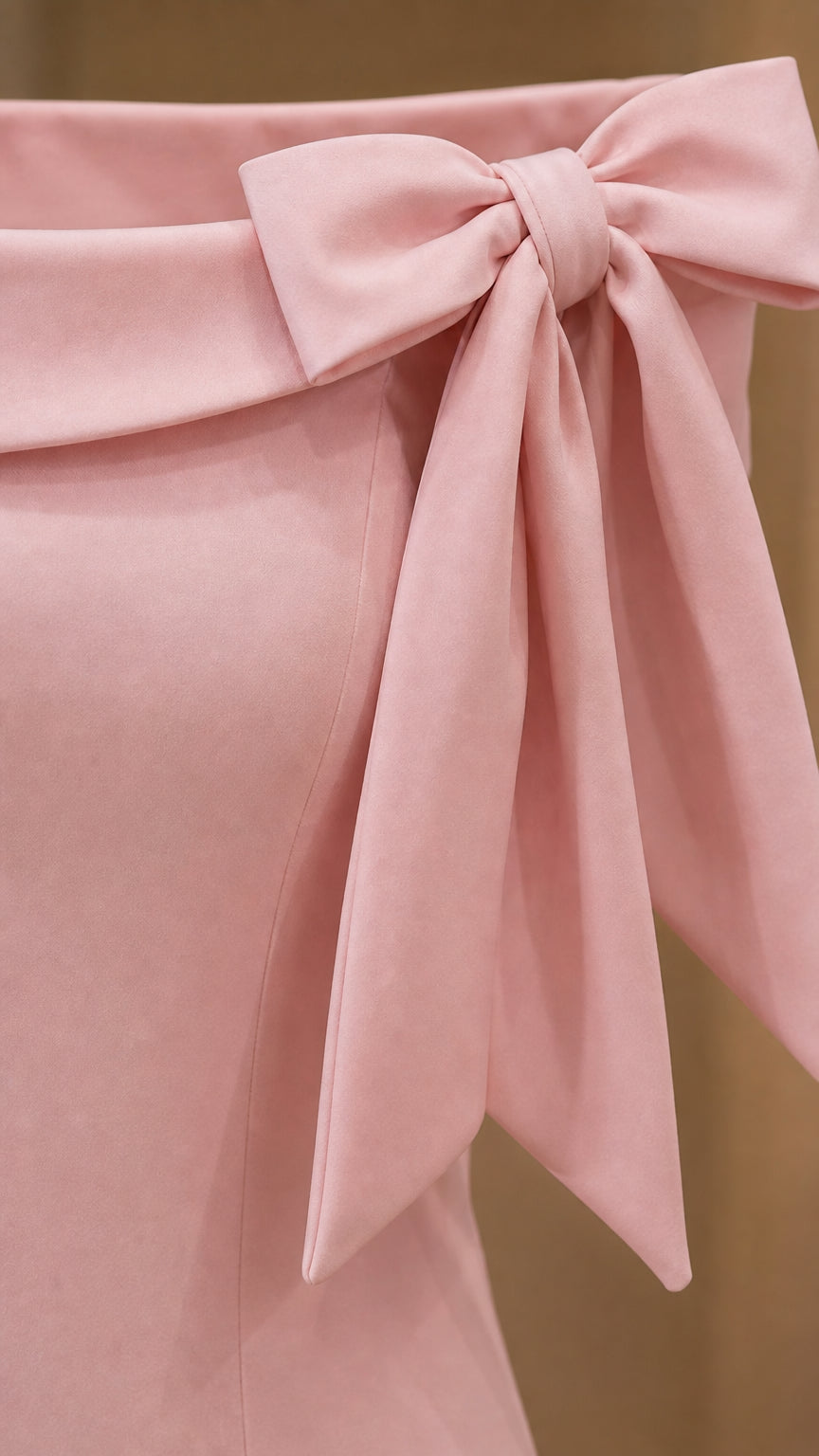 Close-up detail of the structured shoulder bow on the light pink gown