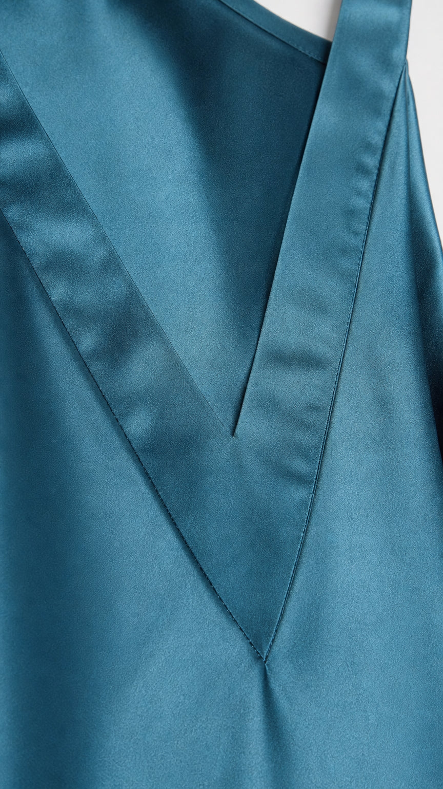 Close-up detail of V-neckline and fabric texture on teal satin dress