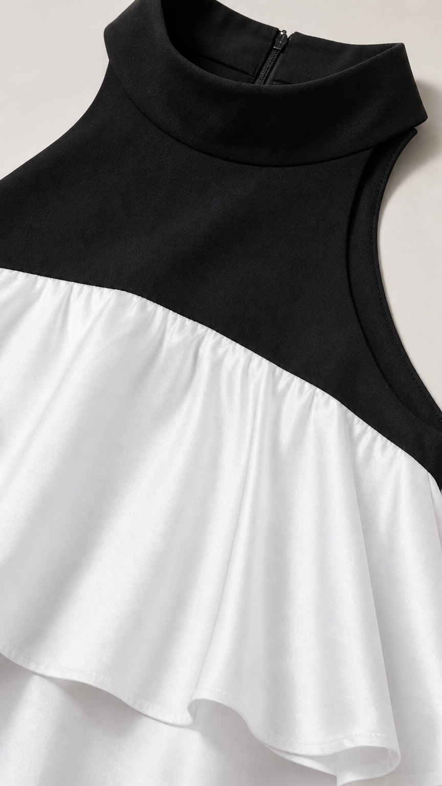 Close-up detail of black mock neck and white ruffle overlay