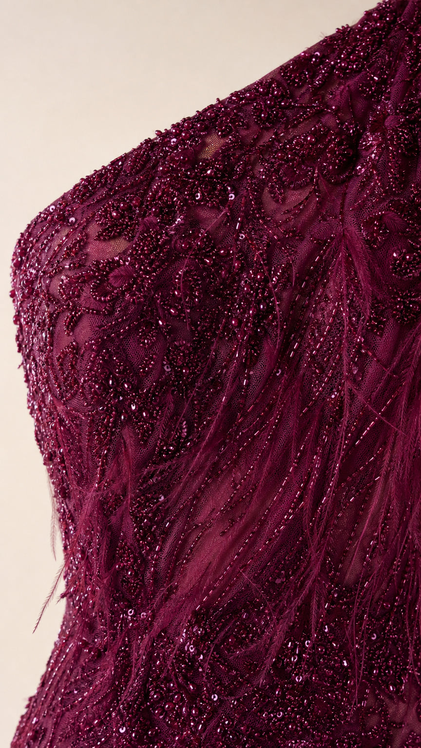 Close-up of intricate beadwork and feather texture on burgundy gown