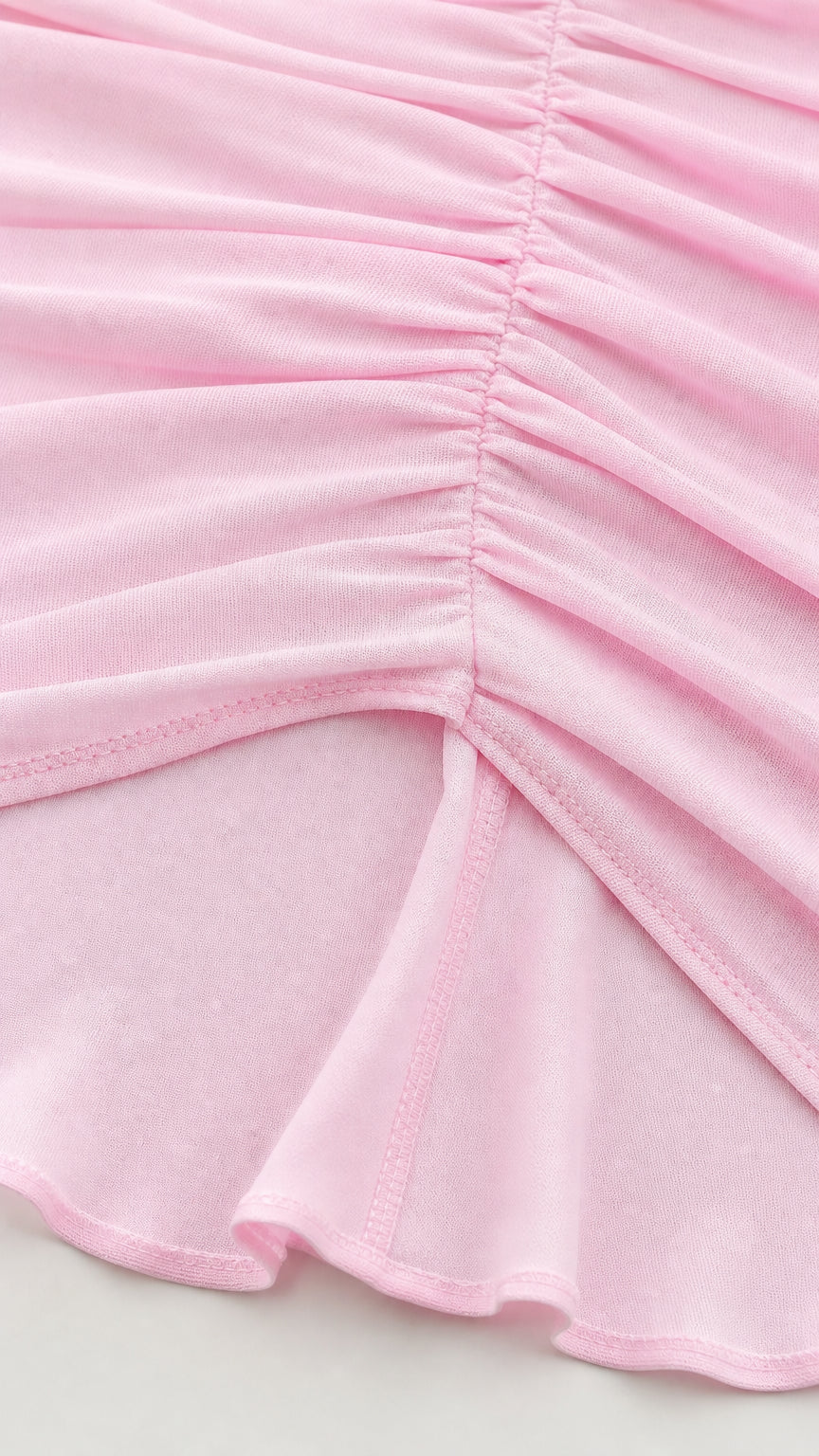 Close-up detail of ruching and hemline on pink dress